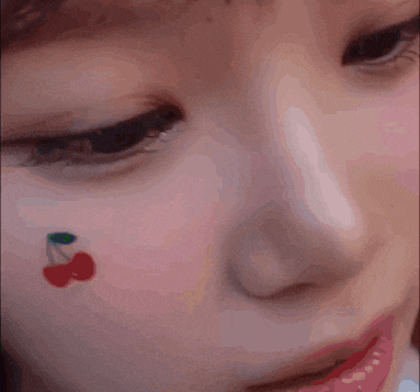 a close up of a woman 's face with a cherry on her face .