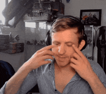 a man wearing headphones and a striped shirt looks at his face