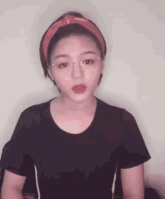 a woman wearing glasses and a red headband is talking to the camera .