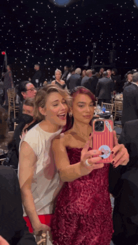 two women are taking a selfie with a phone that has a sticker on it that says " i love you "
