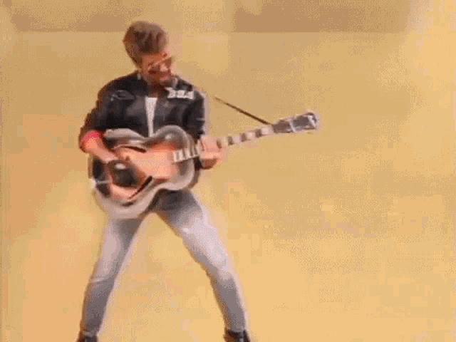 a man is playing a guitar in front of a yellow background
