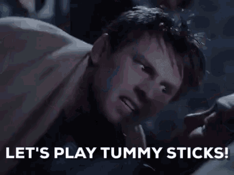 a man is laying on a bed with a woman and says `` let 's play tummy sticks ! ''