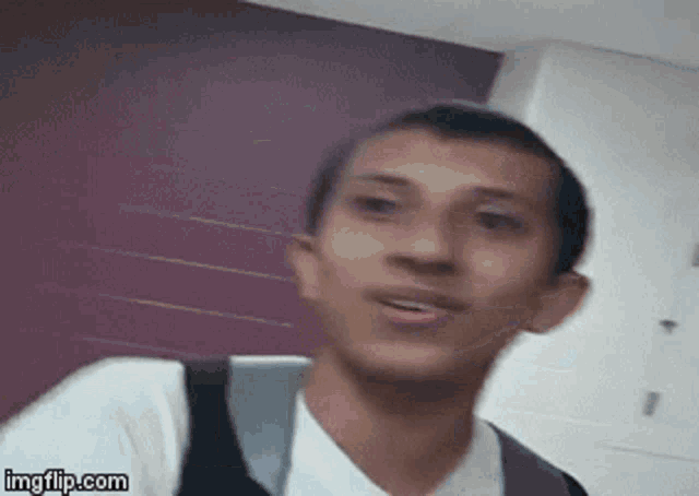 a man with a backpack is making a funny face while looking at the camera .