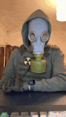 a man wearing a gas mask and a hoodie has a watch on his wrist that shows the time as 8:30