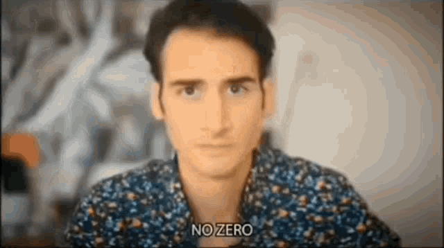 a man in a floral shirt is looking at the camera and saying no zero .