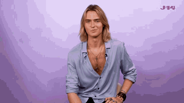 a man with long blonde hair is sitting in front of a purple background with the word j14 on it