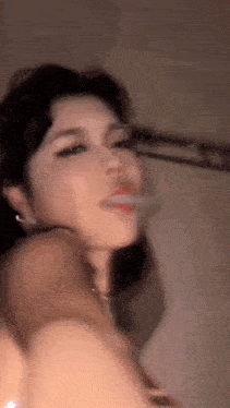 a woman is smoking a cigarette in a blurry video .