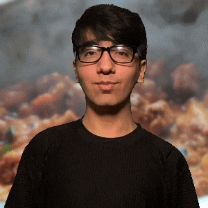 a young man wearing glasses and a black shirt stands in front of a blurred background of food