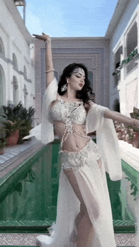 a woman in a white dress is dancing in front of a swimming pool