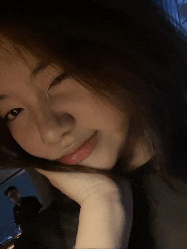 a woman with her hand on her face looks at the camera