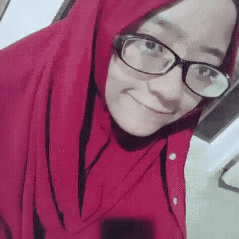 a woman wearing glasses and a red scarf is smiling for the camera .