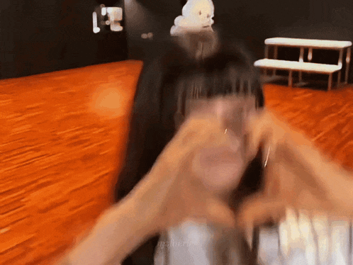a blurry picture of a woman making a heart shape with her hands .