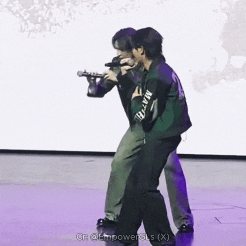 two men standing on a stage with one wearing a green jacket that says martin