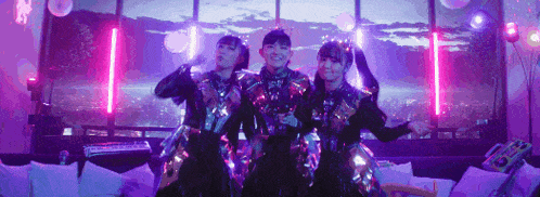 a group of three girls are standing next to each other in a room .