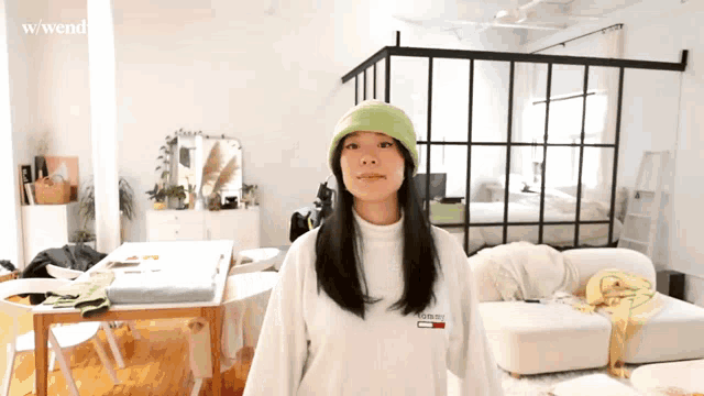 a woman wearing a green hat and a white tommy hilfiger sweater