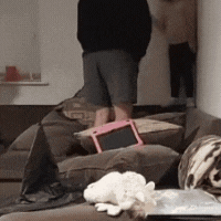 a man is standing on a couch holding a tablet