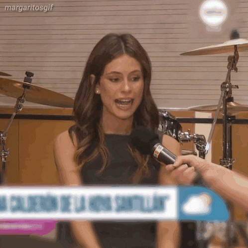 a woman is talking into a microphone with margaritosgif written on the bottom