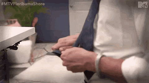 a man in a white shirt is tying a blue tie in a bathroom .