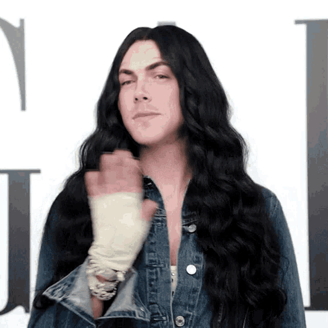 a man with long black hair and a denim jacket
