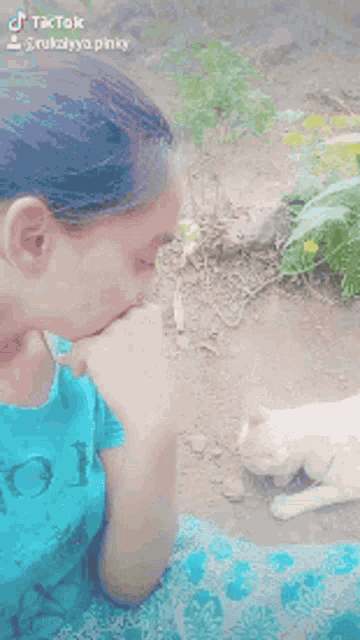 a woman in a blue shirt is playing with a cat