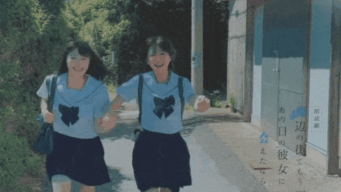 two girls in school uniforms are running down a road