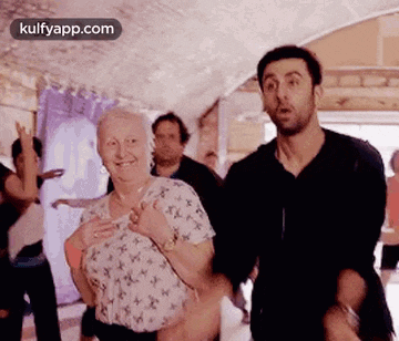 a man is holding an older woman in his arms while dancing in a room .