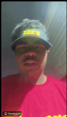 a man wearing a red shirt and a hat with the name cleveland jr on it