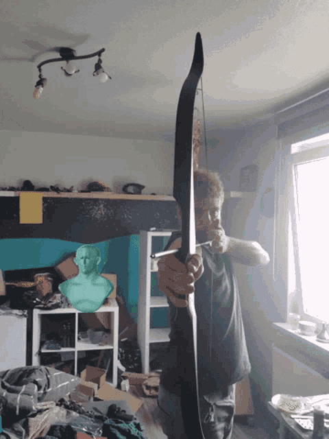 a man is holding a large bow and arrow in a room