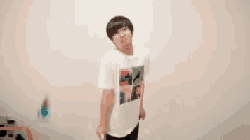 a man in a white shirt is holding a remote control in front of a wall with chinese writing behind him