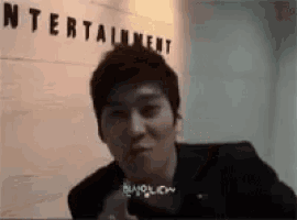 a man sitting in front of a wall that says entertainment