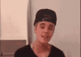 a young man wearing a black hat and a black shirt is talking .