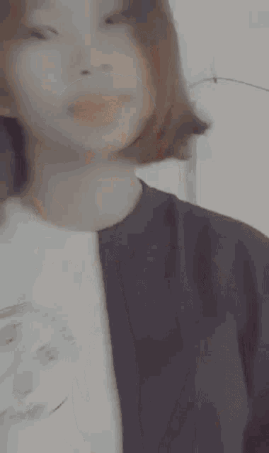 a woman with short hair is wearing a black shirt and a white shirt .