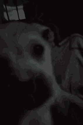 a black and white photo of a person laying on a bed with smoke coming out of their mouth .