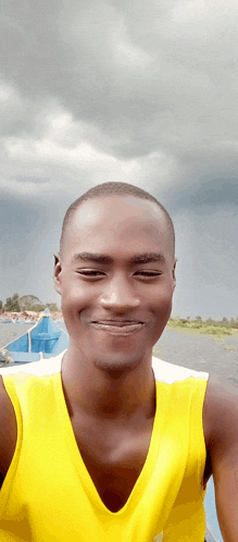 a young man wearing a yellow tank top smiles for the camera
