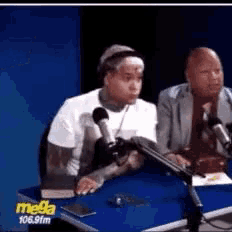 a man is sitting at a table in front of a microphone .