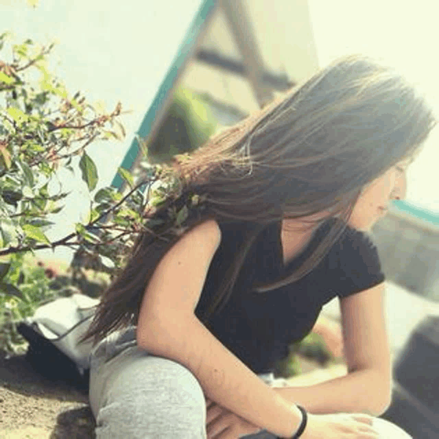 a young woman with long hair is sitting on the ground .