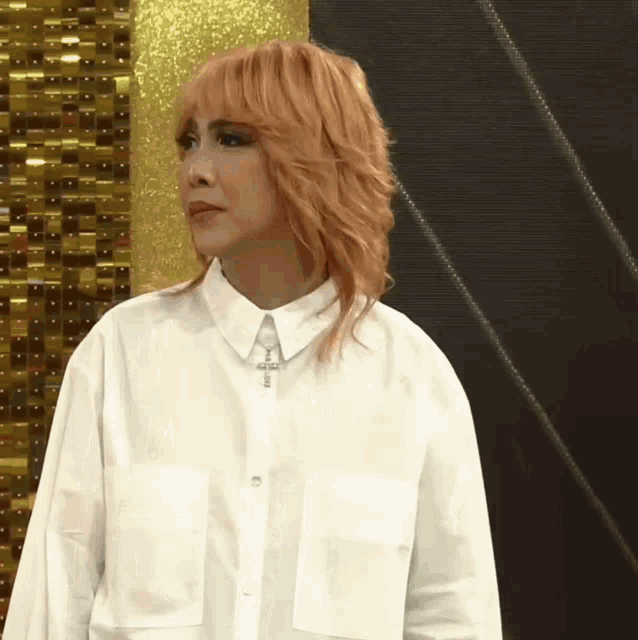 a woman with blonde hair is wearing a white shirt and a cross necklace