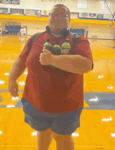 a man in a red shirt is holding two mountain dew bottles .