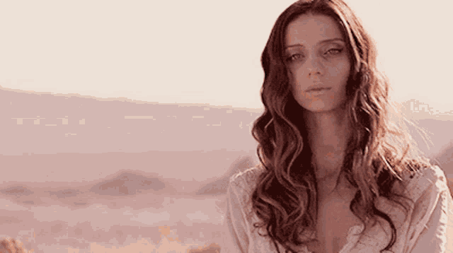 a woman with long hair is standing in front of a mountain