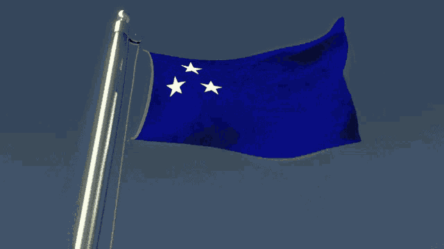 a blue flag with three white stars is flying in the wind
