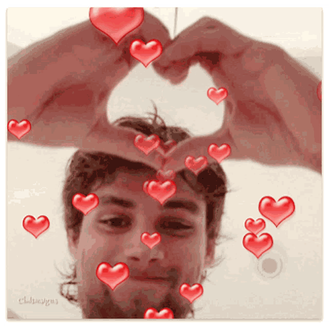 a man is making a heart shape with his hands surrounded by hearts