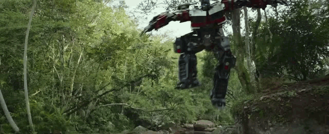 a robot is jumping over a river in a forest .