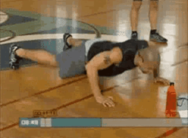 a man is doing push ups on a basketball court with a bottle of water next to him .