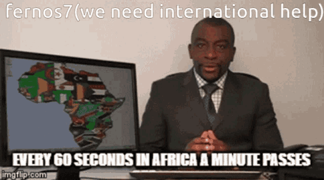 a man in a suit and tie is sitting in front of a computer screen with a map of africa on it
