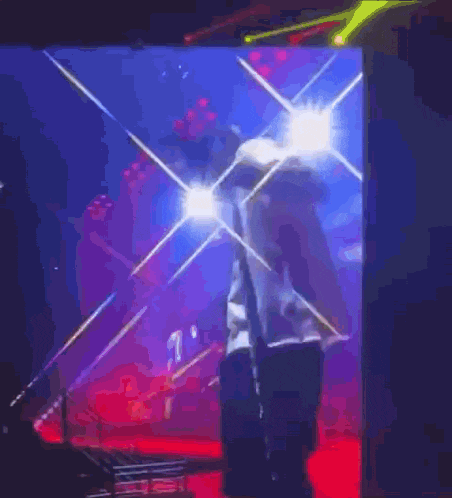 a man in a white shirt is standing on a stage in front of a screen .