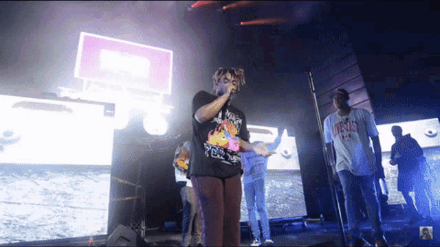 a man singing into a microphone wearing a shirt that says jesus on it