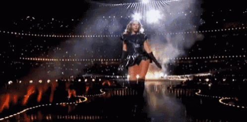 a woman is standing on a stage in a stadium holding a gun .