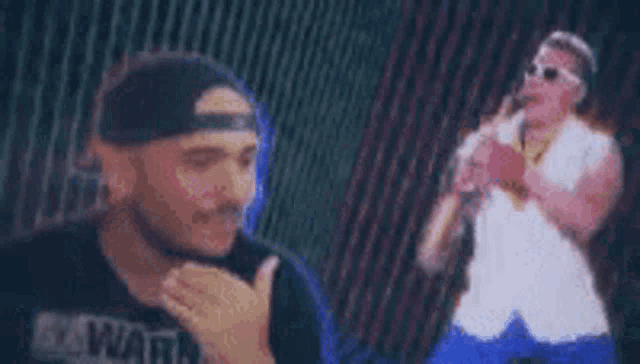 a man in a baseball cap is standing next to a man playing a saxophone on a stage .