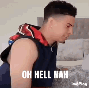 a man wearing a shark hoodie is sitting on a bed with the words `` oh hell nah '' written on the screen .