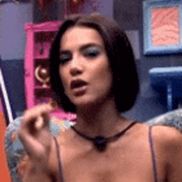 a woman in a very revealing top is sitting on a chair and making a funny face .